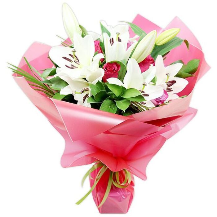 The bouquet in the image is an elegant, hand-tied arrangement that pairs pristine white Oriental lilies with tender pink roses, set against a stark white background so every shape and shade is clearly defined. Rising proudly above the rest, the lilies display large, luxurious blooms, each one a star of layered white petals that curve gently back from the centre. In the heart of each flower, you can see upright stamens tipped with burnt-orange to brown anthers, adding a warm accent and a sense of botanical detail. Some lilies are fully open, while a few buds remain closed or partly split at the tip, in creamy-white and soft green, promising further blossoms and extending the life of the display. Tucked among the lilies, a cluster of pink roses adds softness and romance. Their petals, neatly layered in concentric rings, range from pale, almost pastel pink at the outer edges to a more concentrated rose tone deeper in the centre, giving the impression of depth and tenderness. Around the flowers, lush green foliage spreads out, combining smooth, glossy leaves with slender, grass-like greens, lending fullness and structure reminiscent of expertly tended beds around Brent Cross shopping and nearby residential gardens. The stems are bundled and wrapped generously in shiny pink cellophane or floral wrap that gathers in loose, translucent folds around the blooms, catching points of light and imparting a festive, gift-ready look. At the base, a narrow lime green ribbon is neatly tied, its vivid, fresh tone offering a crisp contrast to the pink and echoing the foliage. This bouquet, likely crafted with care by Brent Cross Flowers for local delivery, would be perfect for celebrations such as birthdays, baby showers, or congratulatory moments, communicating both elegance and gentle affection.