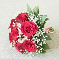 Arranged with the utmost care, this romantic bouquet embodies the spirit of Brent Cross, poised elegantly atop a pale linen reminiscent of North London's beautifully understated interiors. The pièce de résistance is formed by six richly textured red roses, their velvety petals spiraling outward just as the West Hendon roads wind through Brent Cross-bold, intricate, and full of life. Wisps of white baby's breath float between the roses, their dainty clusters creating a dreamy, cloud-soft embrace that softens the bouquet much like the gentle breeze across Brent River Park. Fresh, gleaming green foliage completes the composition, providing contrast and visual harmony, its gentle sheen suggesting a recent morning dew. The stems, expertly bound by skilled florists at Brent Cross Flowers, are wrapped in a vibrant red and white ribbon and crowned with a graceful string of delicate pearls, adding an vintage yet contemporary flourish that catches the eye. Every petal, every ribbon twist, is brought to life by soft, even daylight, emphasizing the bouquet's freshness and the depth of its detail. This arrangement beautifully pairs the tradition of romantic red roses with light, modern touches-its versatility making it perfect for local weddings, anniversary dinners in Brent Cross, or even a heartfelt Valentine's surprise. The subtle perfume of roses mixed with verdant foliage lingers, offering comfort and joy from the heart of the community.