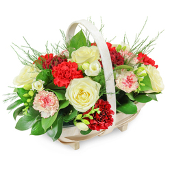 This image shows a beautifully composed funeral flower basket, the sort of thoughtful tribute often chosen in Brent Cross when families want something classic yet reassuringly warm. The flowers are gathered in a pale wooden basket with an oblong shape and a smooth, arching handle, the natural tone of the wood lending a soft, understated character to the design. Four small feet support the base, raising it just enough to give a sense of importance without feeling grand or overpowering. From this quiet foundation, a rounded dome of fresh blooms and foliage spills gently over the edges. Several creamy white roses, fully opened and velvety, take centre stage, their layered petals arranged in serene spirals that naturally draw the eye. Around and between them nestle plentiful carnations: some in a rich, dignified red that suggests steadfast love and honour, others in paler pinks or white petals edged delicately with pink and red, adding nuance and tenderness. Smaller white, bell-shaped blossoms, reminiscent of freesias, appear throughout, their slender stems and clustered florets contributing lightness and a sense of movement. The greenery is lush yet controlled: broad, glossy leaves provide a deep green frame and structure, while airy, fern-like sprigs soften the silhouette and lend the design a natural, garden-inspired feel. The entire composition sits against a bright white background that magnifies the subtle contrasts between cream, crimson, and green. It feels like an arrangement carefully crafted by an experienced local florist, suitable for a funeral or memorial service in Brent Cross, Golders Green, or Cricklewood, or for sending to a bereaved family's home as a gentle message of sympathy and remembrance.