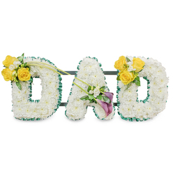 A deeply reverent floral composition spelling out the letters DAD in large, freestanding capitals, each letter built from a thick carpet of immaculate white chrysanthemums that create a plush, even surface and a subtle fresh fragrance. The contours of each letter are neatly edged with a ruffled dark green satin ribbon which gives a crisp, dignified outline; thin, dark green metal bars are visible behind the trio, showing the secure frame that holds them together. The left 'D' is accented on its upper curve with a vivid cluster of bright yellow roses-around three to four blooms-paired with delicate white freesia or gypsophila and rich green foliage; two elongated green stems extend upward and inward from this cluster, adding a gentle, upward movement toward the centre. The central 'A' is grounded by a tasteful arrangement on its lower left diagonal containing two deep purple or burgundy calla lilies, their sculpted, trumpet forms surrounded by small white filler flowers and soft leaves that lend an air of solemn elegance. The right 'D' mirrors the left with the same cheerful yellow rose cluster on its upper right curve, creating a balanced, harmonious tribute. Crafted with care for funeral chapels and memorials across Brent Cross and nearby Mill Hill and Golders Green, this personalised tribute-available through local florists like Brent Cross Flowers-is intended to express respect, comfort, and lasting remembrance for a beloved father.