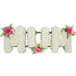 The photograph shows a striking funeral flower tribute spelling out the word MUM in bold capital letters, aligned neatly on a dark green frame and isolated against a clean white background. Every letter is fashioned from a dense blanket of white spray chrysanthemums, each bloom pressed close to the next so the eye reads a continuous field of petals rather than individual stems. The flowers appear fresh and luminous, their small, rounded heads creating a soft, padded texture that invites the imagination to trace each curve and corner. Beneath the flowers, the slim green framework peeps through at the edges, giving the arrangement structure without stealing attention. To soften the formality of the block lettering, the florist has added three identical accent clusters. On the top left of the first M, a vibrant fuchsia rose opens in full bloom, embraced by smaller pink spray roses and closed buds that hint at life continuing. Wispy sprigs of green fern arch from the cluster, introducing a gentle movement that contrasts with the solid white foundation. A second cluster sits snugly at the lower centre of the U, while a third crowns the upper right of the second M, visually balancing the design from left to right. The combination of pure white chrysanthemums and warm pink roses conveys a message of respect, tenderness, and enduring love. This is the kind of bespoke floral lettering families in Brent Cross might choose for a service at a local crematorium or cemetery, a heartfelt way to say farewell to a much-loved mother and to reflect on shared memories and the warmth she brought into their lives.