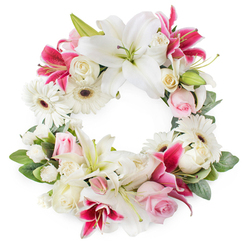 Set against a clean white background, this lush circular wreath is composed as a complete, unbroken ring of flowers, capturing the symbolism of eternal love and remembrance often chosen for funerals and memorials near Brent Cross. At first glance, the eyes are drawn to the large white lilies, their petals velvety and fully open, showing off delicate green pistils and golden stamens that stand out gently against the pure white. Intertwined with these are striking deep magenta and fuchsia lilies, whose star-shaped flowers and subtle speckles lend vibrant contrast, adding a modern touch to a traditional sympathy piece. Soft light pink roses are nestled throughout, some shyly closed in bud and others half-open, their blush tones suggesting gentleness, admiration, and quiet grief. Creamy white roses lend additional fullness, their multi-layered petals creating a classic, timeless look reminiscent of garden shrubs in North West London back gardens. Bright white gerbera daisies, with dark central discs, appear at intervals, offering a cheerful brightness without losing the wreath's dignified mood. Smaller white filler flowers, probably spray carnations or chrysanthemums, are meticulously placed between the larger blooms, forming a soft, cloud-like texture that gives the wreath a plush and complete appearance. Around the outer edge and inner rim, lush green foliage adds structure and contrast, framing the circle of flowers and evoking the greenery surrounding Brent Cross's residential streets. The finished arrangement feels both soothing and respectful, an ideal floral tribute for conveying condolences at a funeral service, crematorium ceremony, or graveside farewell in the Brent Cross area, where families value thoughtful, beautifully crafted funeral flowers.