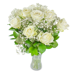 There is a serene composure to this hand-tied display: roughly a dozen immaculate white roses paired with airy clusters of baby's breath, photographed against a spotless white background that keeps attention on texture and tone. The roses, creamy and velvety, reveal petals that curl and overlap in delicate layers; a few are at full bloom, soft and open, while others are still tenderly unfurling, giving the arrangement a natural rhythm and life. Wisps of Gypsophila spill gently between the principal blossoms like drifting mist, their tiny star-shaped flowers creating a luminous softness that contrasts with the broader, more sculptural rose petals. A foundation of verdant leaves - some deep, almost jewel-green and others lighter and springlike - brings a fresh vitality, their veins and satin finishes visible against the glass vase which shows neatly trimmed stems and the clear water line. The lighting feels like a pale London morning, soft and even, so the whites maintain luminosity without glare. As a florist in Brent Cross might note while preparing an order for delivery to a nearby flat or a table at a local café, this bouquet carries a quiet message: comfort, celebration, and thoughtful restraint. Its subtle fragrance is more of a suggestion than a statement, conjuring the calm of a conservatory or the hush of a chapel. Perfect for birthdays, anniversaries, or expressions of sympathy, it speaks gently and with impeccable taste.