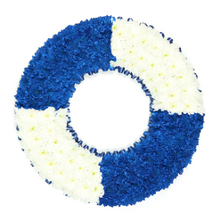 A striking circular floral tribute is carefully arranged to resemble a traditional life ring, photographed against a bright white background so that its bold colours and shapes stand out in calm, clear contrast. The wreath itself is entirely composed of small, closely nestled flowers, likely chrysanthemums, which form a smooth, cushion-like surface across the entire ring. Divided into four equal sections, the ring alternates between a deep, royal blue and a crisp, pure white, creating a strong nautical look you might associate more with riverside scenes than the busy streets around Brent Cross Shopping Centre. The top left and lower right quadrants glow with an inky blue intensity, each tiny petal contributing to a richly layered field of colour that feels contemplative and steady. Opposite them, the top right and lower left sections are made up of immaculate white blooms that catch the light, bringing an air of tranquillity, remembrance, and release. The transitions between the coloured blocks are neat and precise, giving a sense of careful craftsmanship and intention. Encircling the inner edge of the wreath is a narrow band of dark blue ribbon, gently ruffled, which frames the hollow centre and subtly echoes the ropes or edging of a real lifebuoy while never taking attention away from the flowers. The open centre of the ring is clearly visible, reinforcing the symbol of protection, a guiding presence, and the idea of being held safely through life's rougher waters. This design works beautifully as a funeral wreath or condolence tribute for someone with maritime ties or a reputation as a "lifesaver" in their family, and it is the sort of thoughtful piece that Brent Cross Flowers might prepare for delivery to local chapels or crematoria.