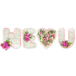 Set against a crisp white background, this made-to-order tribute forms the sequence H, E, a heart, and U - a visual message crafted to read as a warm, unmistakable expression of love or remembrance. Each letter H, E and U is constructed from compact white chrysanthemums that create a cushiony, cloud-like surface; the edges are traced with a pale blush satin ribbon, its subtle sheen softening the shapes and lending an almost handwritten tenderness. The H is punctuated at its lower left by two saturated fuchsia roses, clusters of small red berries, and fine, dark green, ferny foliage that offer contrast in colour and texture. The E carries a central cluster of three fuchsia roses along its middle bar, pulling the composition together with a confident pop of magenta. Center stage, the heart is filled with layered blush and soft-pink blooms - spray carnations, pale lisianthus or petite roses - interleaved with pale green eucalyptus leaves that add a dusty, aromatic freshness and gentle movement. The U repeats the white chrysanthemum construction and blush ribbon border, finished with a tucked pair of fuchsia roses and deep green leaves in its inner curve to mirror the left-hand accent. The overall impression, seen in soft daylight or a quiet chapel, is one of careful craftsmanship and emotion: the purity of white suggests peace, while the vibrant pinks convey admiration and affection. Created with local care for clients around Brent Cross Shopping Centre, Hendon and Staples Corner, this design is available from Brent Cross Flowers for families seeking a personalised tribute or an intimate declaration of love.
