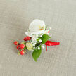 Arranged with the careful hand of a Brent Cross florist, this boutonnière centers on a pristine white phalaenopsis orchid whose creamy petals open like fine porcelain, revealing a gentle yellow-orange throat that draws the eye inward. A halo of delicate gypsophila - Baby's Breath - drifts around the orchid, their tiny, cloud-like blossoms lending an ethereal softness and whispering romance. Bright red hypericum berries are tucked in at the base in small glossy clusters, their vivid colour echoing the scarlet satin ribbon that secures the stems and finishes the piece with a confident flourish. Slender, pale green buds and smooth deep-green foliage - likely salal - provide fresh structural contrast and a sense of living growth. The boutonnière lies on a warm, light beige textured fabric, perhaps linen or burlap, which gives the arrangement a natural, tactile stage beneath gentle light. As a design I would offer at Brent Cross Flowers for weddings, proms or formal events around Brent Cross, Hendon and nearby Cricklewood, it balances traditional bridal restraint with a hint of festive cheer. Imagine it pinned to a groom's lapel outside a reception near Brent Cross Shopping Centre or carried by a proud parent to a local community hall: the combination of creamy orchid, frothy gypsophila and ruby berries reads as refined, celebratory and intimately made. The overall impression is one of poised elegance - small, tactile, and thoughtfully finished for the important moments it will accompany.