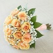 This hand-crafted bouquet radiates a poised, gentle grace, capturing the magic of a Brent Cross celebration. Each rose in the arrangement opens in a graceful spiral, its petals shaded from creamy peach to luminous apricot, reminiscent of early spring blooms in Brent Cross's hidden gardens. Wispy gypsophila drapes softly between the roses, echoing the airy lightness of lace or the delicate promise of a new season. Shiny, dark green leaves frame the pastel cluster, providing a lively backdrop and evoking the lushness of Brent Cross's parks and tree-lined streets. The expertly tied stems are wrapped in smooth peach satin, elegantly decorated with rows of pearl beads that catch the daylight much like glistening morning dew on local lawns. Resting against a soft, pale backdrop, every aspect of the bouquet is highlighted-colour, texture, and artistry-conveying quiet anticipation and fresh beginnings. A faint note of sweet rose scent drifts from the bouquet, ideal for a meaningful ceremony, anniversary, or an intimate wedding at a local Brent Cross venue. Designed for those who value timeless beauty and local expertise, this bouquet is prepared with care for special deliveries across Brent Cross and surrounding areas.