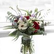Artfully composed, this bouquet is a testament to Brent Cross's love for striking colour and harmonious design, featuring lush crimson roses that command attention alongside creamy white gerberas, their petals glowing softly as they catch the natural North West London light. Ethereal lisianthus, in tender shades of pale lilac and violet, peek out from between swathes of aromatic eucalyptus, their round, silvery discs reflecting the soft daylight found in homes near Brent Park or Temple Fortune. Tucked close, cushion-like ivory filler blooms lend the arrangement a delicate fullness, while broad, shiny green leaves create a structured cradle, highlighting the bouquet's dynamic layering. The transparent vase reveals sturdy, vibrant stems, a sign of their day-fresh harvest. Softly fragrant with the mingled notes of rose and eucalyptus, the bouquet is as uplifting as a stroll along Brent Cross's local paths, suited for joyful milestones, thoughtful gestures, or simply bringing a breath of open-air beauty indoors-lovingly designed by Brent Cross Flowers.
