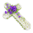 A traditional yet contemporary floral cross, appropriate for a funeral or memorial, is presented on a clean white background, photographed from above so its shape and detailing are perfectly clear. The body of the Christian cross is covered entirely with small white chrysanthemums, packed closely together so there is no visible foliage or gaps, just a soft, plush surface of tiny, neatly arranged petals. The flowers' subtle green centres add minute dots of colour, giving the white expanse a quiet, living texture. Following the outer contour of the cross is a slim border of lime-green ribbon, neatly attached and slightly glossy, which outlines the form and introduces a fresh, spring-like accent that feels hopeful rather than sombre. At the very centre of the cross, where the arms intersect, a substantial cluster of deep royal purple lisianthus creates a rich focal statement. The velvety petals of the lisianthus are arranged in layered spirals, some blooms wide open and others in gentle bud, providing a natural variety of shapes and depths. Threaded through this central grouping are fine, light green leaves and a few delicate fillers, which add softness and dimension. From this heart of colour, several lisianthus stems continue downwards along the right side of the cross, their blossoms and buds forming a graceful diagonal trail that seems to flow over the white chrysanthemums. A faint, natural shadow beneath the arrangement gives a sense of three-dimensionality. This tender, faith-inspired tribute echoes the style often requested by families in Brent Cross and around Hendon Way, ideal for accompanying a coffin, resting by a memorial photo, or marking a graveside as a symbol of love, respect, and spiritual comfort.