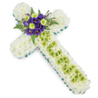 The image features a refined floral cross, designed as a sympathy tribute and set clearly against a white background so every detail can be appreciated. The entire surface of the cross is densely covered with pristine white chrysanthemums, each bloom sitting closely beside the next to form a soft, cloud-like foundation that radiates purity and calm. Along the edge, a precise border of fresh green ribbon or carefully arranged foliage delineates the cross's outline, giving it a clean, structured finish that feels well suited to modern memorial services in and around Brent Cross and nearby Temple Fortune. Down the centre of the long vertical arm, a striking stripe of lime green button chrysanthemums runs in a straight, gentle band. These rounded flowers provide a refreshing contrast to the white cushion beneath, adding a sense of life and renewal. Draped over this green section, fine pale green wires create a faint yet deliberate criss-cross pattern, like a delicate net that adds texture without overwhelming the flowers. At the central crossing point of the arms, a compact spray of deep purple lisianthus draws the eye. Their velvety petals, layered and slightly ruffled, are grouped with bright lime green blooms that echo the vertical stripe. Behind and around this cluster, dark green fern fronds and complementary foliage fan out softly, adding depth and a natural frame. The colour palette of white, green, and purple creates a feeling of quiet dignity and hope. Intended as a funeral cross or memorial tribute, this arrangement offers a tender expression of sympathy and remembrance for families across the Brent Cross community.