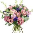 A carefully composed, hand-tied bouquet is photographed against a stark white background, making its colours and textures vividly clear. At its centre, roses in shades of dusty rose, muted mauve, and pale peach open in soft spirals, some fully blossomed with wide, cupped petals, others still in partially closed buds that give the arrangement a sense of life and unfolding time. Surrounding them are lush, ruffled carnations, each petal edge brushed with vivid magenta that gradually fades into a creamy blush interior, creating a subtle gradient across the blooms and adding plush texture. Among these gentle hues, deep indigo and violet-blue anemones appear like small jewels, their petals encircling dark, almost black centres that draw the eye and bring a dramatic note to the pastel palette. Tall stems of lavender and pale pink stock weave upward through the bouquet, their dense clusters of tiny florets lending a soft, feathery dimension and a suggestion of delicate fragrance. The flowers are framed by an ample collar of greenery, with rounded, silvery eucalyptus leaves and darker, broader foliage overlapping in layers, forming a full, rounded outline. The natural green and woody stems are gathered tightly at the base, clearly hand-tied, giving the impression that the bouquet has just been completed by a florist at Brent Cross Flowers, perhaps moments before being delivered to a home near Brent Cross Shopping Centre, along the North Circular, or into one of the nearby residential streets. The overall mood is romantic yet modern, making this bouquet suitable for anniversaries, thoughtful thank-you gifts, or simply bringing a sense of calm, elegant colour to a living room in the Brent Cross neighbourhood.