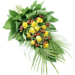 A long, teardrop-shaped funeral spray of yellow roses is pictured against a plain white background, its design flowing elegantly from the fuller top left down towards the slender tip at the lower right. Central to the arrangement is a cluster of approximately fifteen to twenty yellow roses, carefully spaced so that each bloom can be appreciated. Some of the roses are still gathering themselves into tight buds, while others have opened generously, their velvety petals forming soft, concentric circles that catch the light. The yellow tones are warm and comforting, evoking gentle memories and gratitude. Between the roses, clusters of small, round red Hypericum berries appear, their deep, polished red bringing contrast and a touch of richness. These berries sit snugly amongst a bed of varied green foliage. At the top left, strong, broad leaves have been folded and wrapped into a solid backing, providing a supportive base that gives the spray its structure. Closer to the centre, mid-sized leaves and smaller greens weave around the blooms, filling gaps and adding texture. From the lower right, long palm-like fronds sweep outward and downward, their narrow, pointed leaflets overlapping like feathers, giving the arrangement a sense of movement and grace. The stems are neatly tied, ensuring the piece lies flat and poised, ready to be placed on a coffin, memorial plinth, or graveside at a service in Brent Cross or the surrounding North West London area. The combination of sunny yellow, deep red, and lush green, viewed under soft, even light, conveys a quiet message of respect, remembrance, and supportive presence.