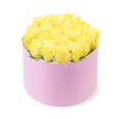 A chic, pastel pink hatbox brimming with yellow roses is photographed against a crisp white background, creating a fresh, contemporary portrait of floral luxury. The cylindrical box appears smooth and matte, its soft blush tone hinting at a fabric-like, velvety texture that invites the imagination to feel its surface. From the top of the box, around two dozen yellow roses are arranged in a compact, gently domed cluster, their heads aligned so closely that they form a continuous field of petals. Each rose is captured at the ideal point of bloom, with layered petals that spiral outward from a more buttery, pale yellow centre to brighter, sunlit edges, giving the bouquet a lively yet soothing presence. Small touches of dark green foliage peep discreetly through the blooms, adding subtle depth and reminding you that this polished design still comes from living stems. The lighting is soft and evenly distributed, with no strong shadows, helping every curve of the petals and every nuance of yellow to be clearly imagined. This arrangement feels like something you might have delivered to a friend near Brent Cross Shopping Centre after a shared day out, or as an elegant birthday surprise for someone living close to the leafy streets around Golders Green. It carries the emotional notes of cheerfulness, gratitude, and affectionate friendship, all grounded in a modern hatbox style that reflects the taste of a skilled Brent Cross florist who knows how to balance colour, texture, and sentiment in a single arrangement.