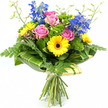 Photographed against a crisp white background, this joyful bouquet appears freshly arranged and ready to leave Brent Cross Flowers for a special delivery. At its core, several pink roses open in soft, spiralling layers, their silky petals overlapping to create a focal point of romance and gentle warmth. Encircling these are bright yellow gerbera daisies with rich, dark brown centres, their wide, evenly spaced petals forming bright halos of colour that bring an instant sense of optimism, like a patch of sunshine breaking through over Brent Cross. Rising through the centre and towards the back, tall stems of deep blue delphinium draw the eye upward; clusters of small florets along each stem provide a cool, elegant counterbalance to the warmer roses and gerberas below. The bouquet is generously framed by lush greenery: fine, feathery fern fronds cascade softly from the edges, while broad, glossy green leaves curve around the lower blooms in a smooth, structured collar, some gently striped with paler green tones. Tucked among the main flowers, bright green, cushiony filler foliage fills out the spaces, giving the arrangement a dense, garden-fresh fullness. Slender, light green stems tipped with tiny unopened buds stretch delicately above the main floral canopy, adding an airy, youthful energy. At the bottom, the natural stems are visible, neatly aligned and bound together with a simple, natural-looking tie that highlights the hand-tied nature of the design. The overall impression is of a vibrant, contemporary bouquet - ideal for celebrating milestones, sending congratulations, or simply lifting someone's spirits around Brent Cross with a colourful burst of fresh flowers.
