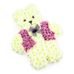 A soft, teddy bear-shaped floral arrangement fills this frame, designed as a gentle tribute that feels both playful and deeply comforting. The bear is entirely made from fresh flowers, with the main body covered in tightly packed white chrysanthemums, their small, layered petals forming a thick, velvety surface. The blossoms are expertly placed to follow the contours of a seated bear, shaping rounded ears, a full head, a plump torso, and short, steady legs and arms that seem ready to offer a hug. The face is composed with care: two small, dark eyes give the bear a sweet, attentive gaze, and a tiny black triangular nose sits just above a soft hint of a pink smile, adding a touch of personality and warmth. Across the front of the figure, a vest of deep pink to magenta chrysanthemums is arranged in tidy sections, echoing the look of a tailored waistcoat and bringing a vivid burst of colour to the otherwise white design. Resting at the neckline is a sheer purple net bow, its delicate loops and trailing ends lying lightly on the petals and providing a graceful finishing touch. The clean white backdrop and even lighting make every texture and shade clearly visible, lending the tribute a serene, almost ethereal quality. This floral teddy bear is often chosen by families in and around Brent Cross-whether for a child's funeral near Clitterhouse Playing Fields or a quiet memorial service off Finchley Road-as a tender symbol of love, innocence, and the desire to hold someone close in memory.